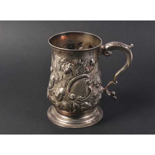 26 - A Georgian Silver Rococo Floral embossed Mug with a Flying Scroll Handle. Weighing: 321 grams.