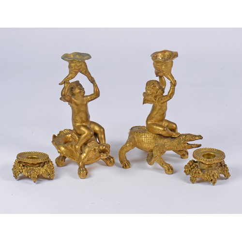 663 - A Pair of Gilded Bronze Candlesticks representing two Cupids or cherubs sitting on crocodiles, holdi... 