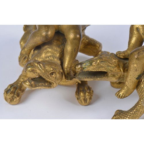 663 - A Pair of Gilded Bronze Candlesticks representing two Cupids or cherubs sitting on crocodiles, holdi... 