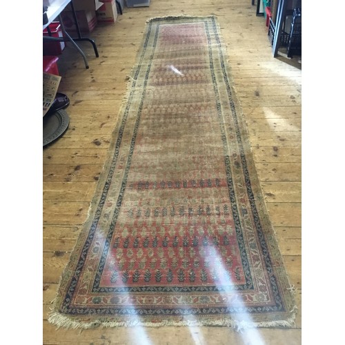 702 - An Antique Hand Made Persian Runner in Poor Condition. Measuring: 381cms x 101cms.