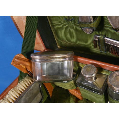 36 - A 1920s Leather Cased Travelling Vanity Case containing Silver mounted Mirror, Two Brushes, Shoe, Bu... 