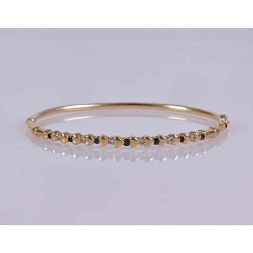 39 - A 9ct gold bangle designed with heart motifs, set with six diamonds and seven emeralds, and fitted w... 