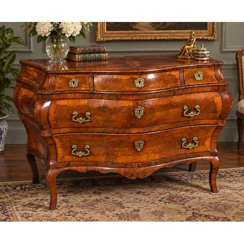 An Antique French Chestnut, Holly & Sycamore banded Bombe Front Commode fitted Three Shaped Topped Drawers, Two Concaved Bottom Drawers with Heavy Cast Brass Handles, Floral Escutcheons & resting on elongated Square Feet.. Measuring: 144cms across x 72cms deep x 90cms high.