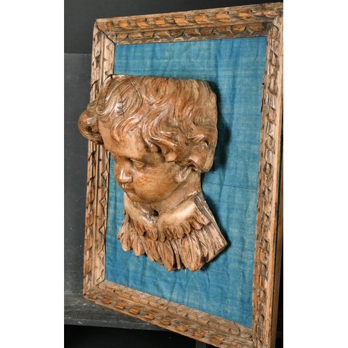 36 - 19th Century European School. A Winged Putto, Carved walnut on a blue silk backing within a carved f... 