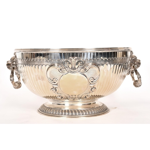 357 - An extremely large Victorian silver punch bowl with lion mask handles and relief decoration, by Jame... 