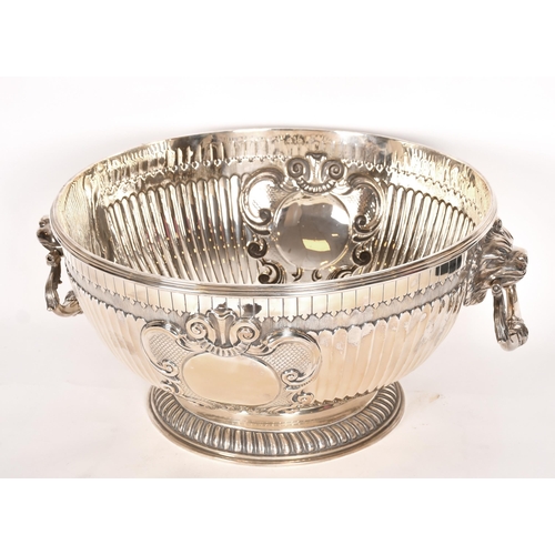 357 - An extremely large Victorian silver punch bowl with lion mask handles and relief decoration, by Jame... 