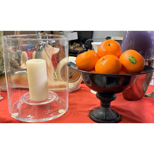 203 - METAL STEMMED BOWL OF ARTIFICIAL ORANGES & LARGE GLASS CANDLE HOLDER WITH CANDLE