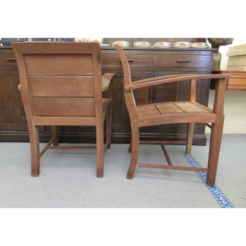 345 - A pair of modern teak patio chairs, each with a solid backs and seats, raised on block legs