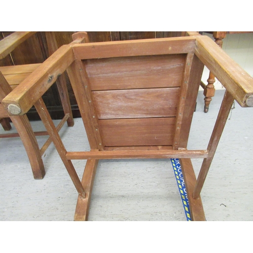 345 - A pair of modern teak patio chairs, each with a solid backs and seats, raised on block legs