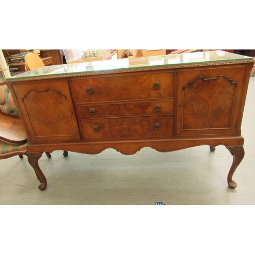 69 - A mid 20thC Waring & Gillows walnut finished sideboard with a carved edge, comprising three draw... 