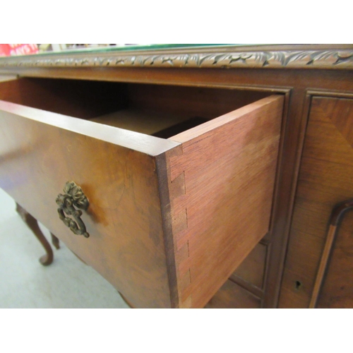 69 - A mid 20thC Waring & Gillows walnut finished sideboard with a carved edge, comprising three draw... 