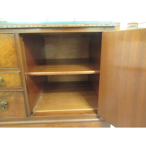 69 - A mid 20thC Waring & Gillows walnut finished sideboard with a carved edge, comprising three draw... 