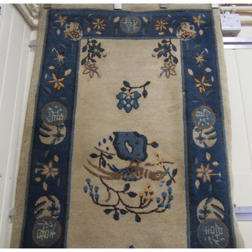 179 - A 1950/60s Chinese woollen rug, decorated with birds and flora with a blue border, on a cream ground... 