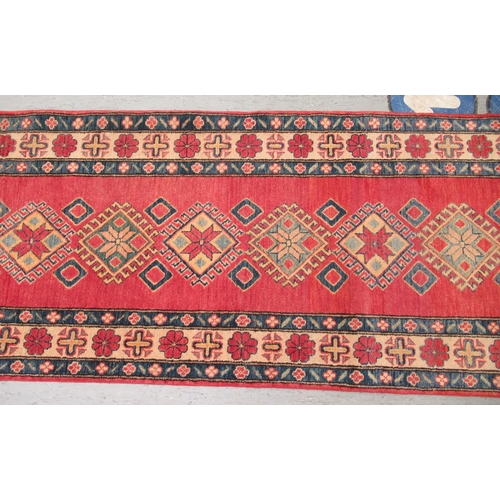 188 - An Afghan Kazak runner, decorated with repeating central diamond shaped motifs, on a multi-coloured ... 