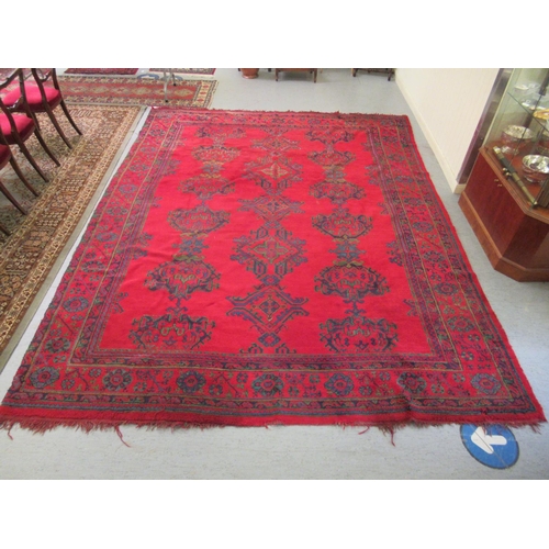 190 - A Persian carpet, decorated with stylised designs, on a red ground  140