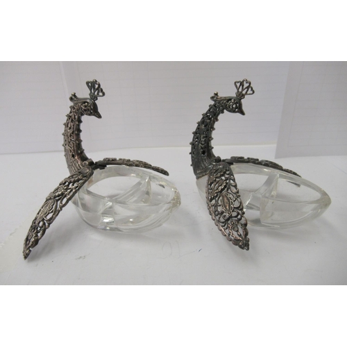 77 - A pair of salt cellars, each fashioned as a Bird of Paradise, the cut glass bowls surmounted by a si... 