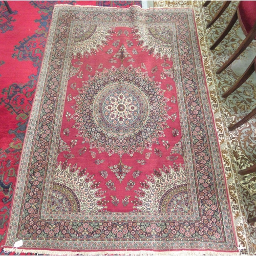 181 - A Persian rug, decorated with a central starburst design medallion, bordered by floral designs, on a... 