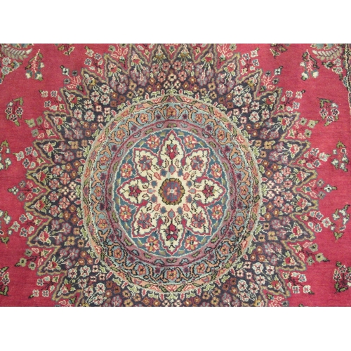 181 - A Persian rug, decorated with a central starburst design medallion, bordered by floral designs, on a... 