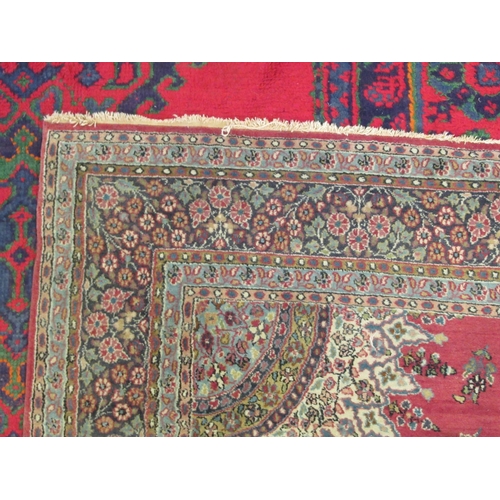 181 - A Persian rug, decorated with a central starburst design medallion, bordered by floral designs, on a... 