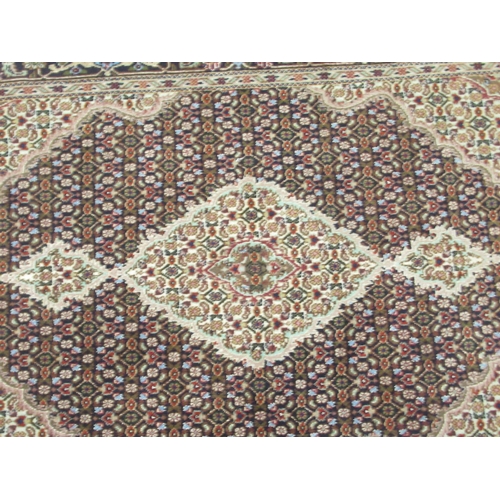 102 - A part silk woven Tabriz rug, decorated with flower head and other stylised designs, on a multi-colo... 