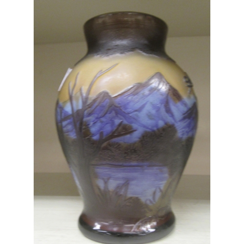 124 - In the manner of Galle, a coloured glass vase of waisted, tapered form, decorated with a mountainous... 