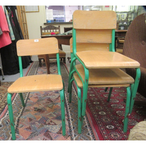 127 - A set of four mid 20thC stacking schoolroom chairs with riveted plywood backs and seats, raised on g... 