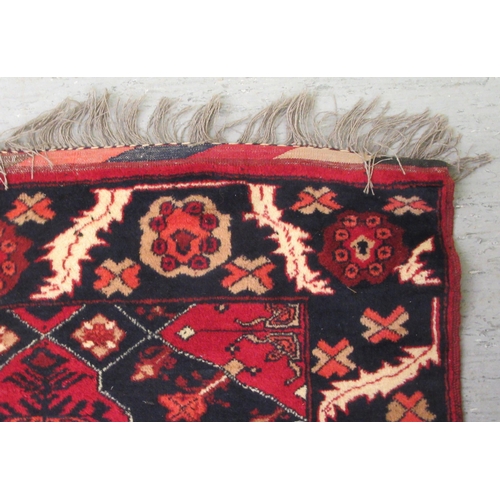 129 - A Kazak rug, decorated with stylised foliate designs, on a red and black ground  36