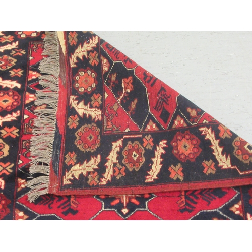 129 - A Kazak rug, decorated with stylised foliate designs, on a red and black ground  36