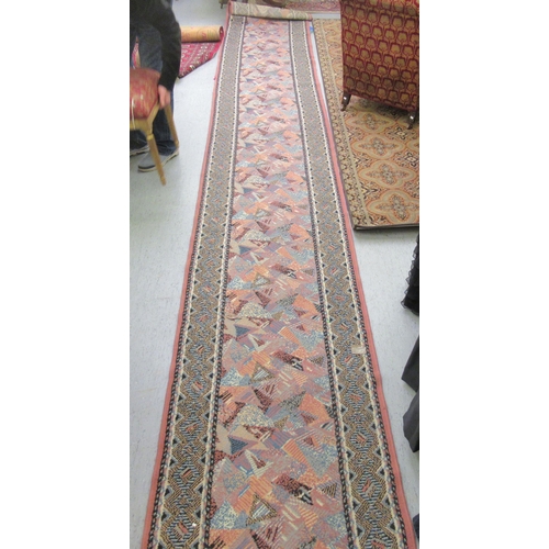 189 - An (off-cut) machine made runner, decorated in 1970s taste on a multi-coloured ground  32