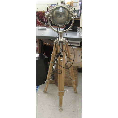 191 - A cast metal standard lamp, fashioned as a spotlight, on a height adjustable teak tripod stand ... 