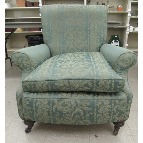 226 - An early 20thC armchair, having a high, scrolled back, upholstered in floral patterned green fabric ... 