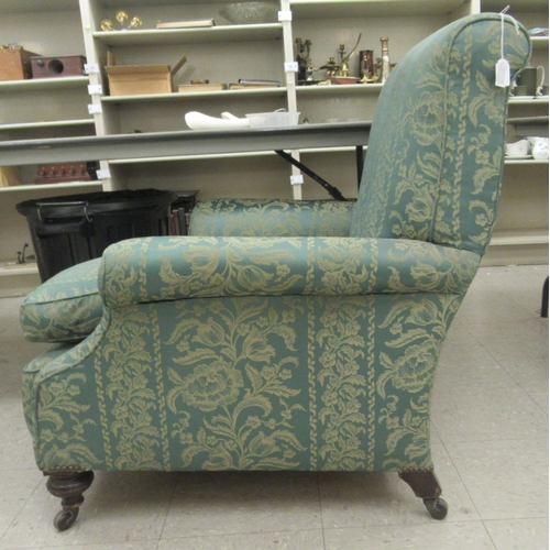 226 - An early 20thC armchair, having a high, scrolled back, upholstered in floral patterned green fabric ... 