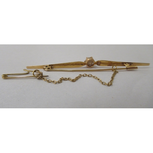 229 - An 18ct gold bar brooch, claw set with a seed pearl, on a safety chain 