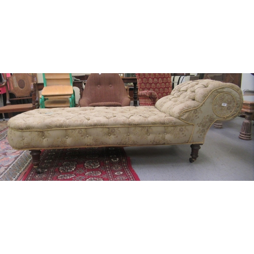 234 - A late Victorian chaise longue, button upholstered in a charcoal floral patterned fabric, raised on ... 