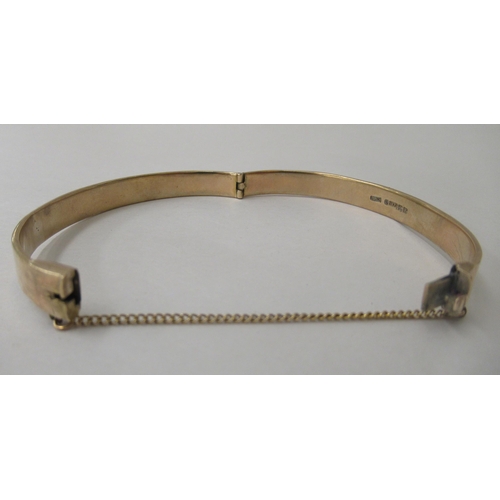 241 - A 9ct gold hinged bangle, on a safety chain 