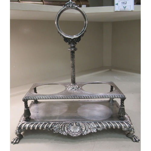 252 - An early 20thC silver plated tantalus stand with a fixed centre handle, provision for two bottles an... 