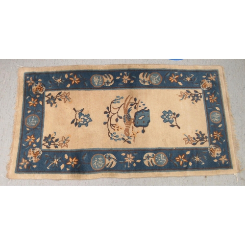 77 - A Chinese woollen rug, decorated with birds and flowers, on a dark blue and cream coloured ground&nb... 