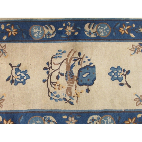 77 - A Chinese woollen rug, decorated with birds and flowers, on a dark blue and cream coloured ground&nb... 