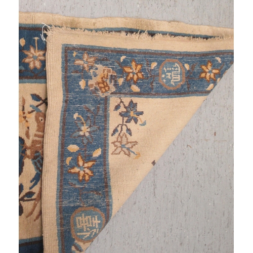 77 - A Chinese woollen rug, decorated with birds and flowers, on a dark blue and cream coloured ground&nb... 