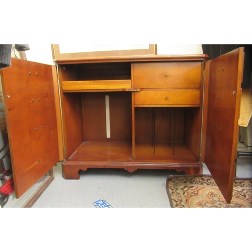 92 - A modern yew finished record cabinet with two doors and a hinged lid, raised on bracket feet  33