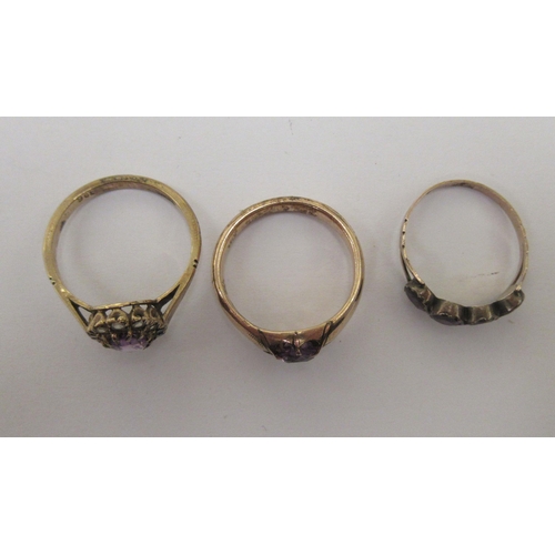 97 - Three yellow metal rings, variously set with purple stones 