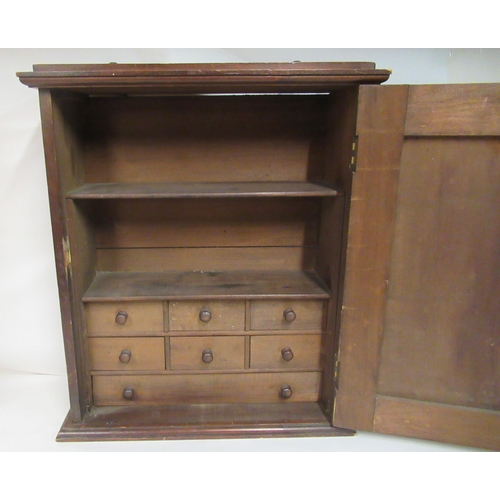 127 - A late 19th/early 20thC stained pine hanging cabinet, the relief carved panelled door enclosing an a... 