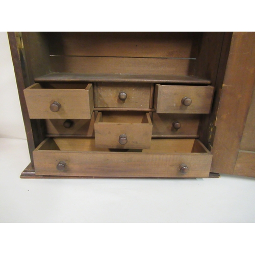 127 - A late 19th/early 20thC stained pine hanging cabinet, the relief carved panelled door enclosing an a... 