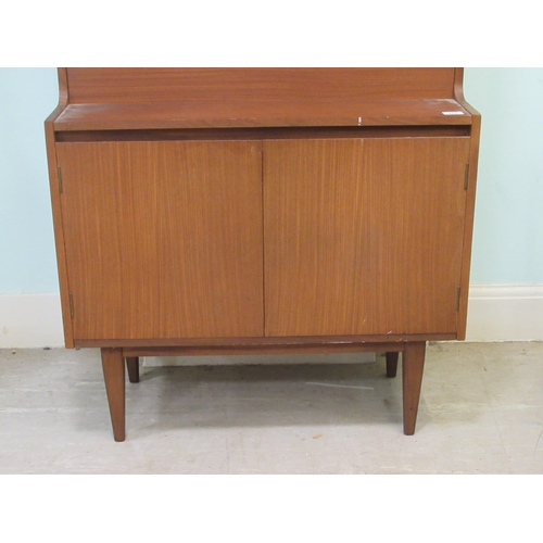 259 - A 1960s/70s teak living room unit with an arrangement of open shelves, doors and a fall flap, raised... 