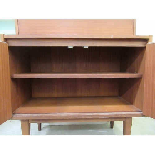 259 - A 1960s/70s teak living room unit with an arrangement of open shelves, doors and a fall flap, raised... 
