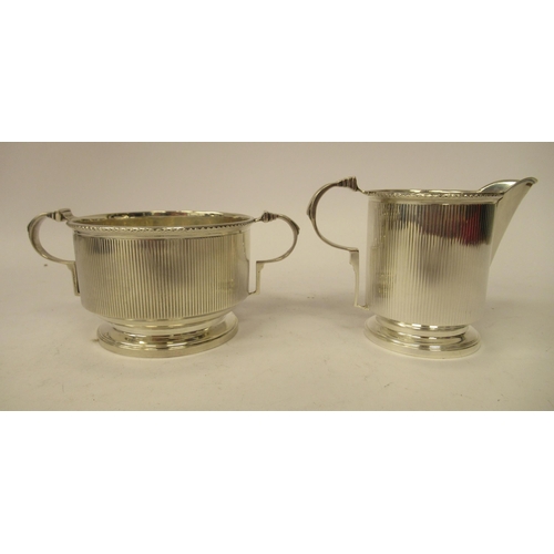 130 - A three piece silver tea set of cylindrical form with vertically line engraved ornament&nbsp; compri... 