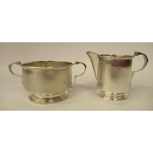 130 - A three piece silver tea set of cylindrical form with vertically line engraved ornament&nbsp; compri... 