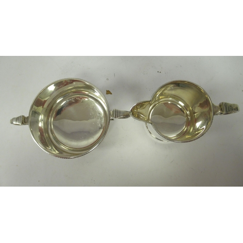 130 - A three piece silver tea set of cylindrical form with vertically line engraved ornament&nbsp; compri... 