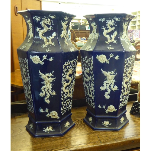 102 - A pair of modern Chinese porcelain blue glazed vases of octagonal form, decorated in relief with dra... 