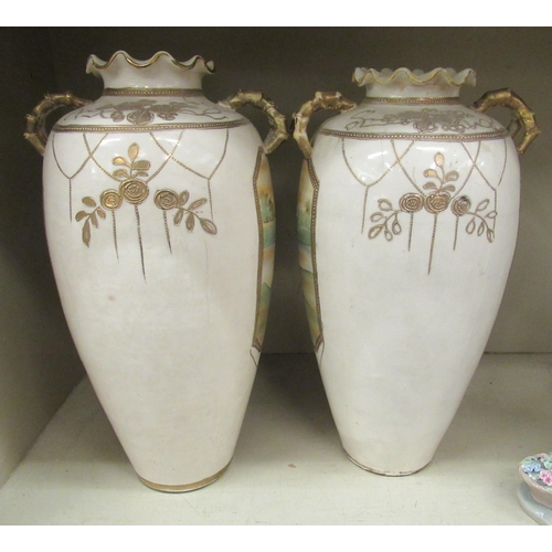 103 - A pair of 20thC Japanese twin handed porcelain baluster shaped vases, decorated with pictorial vigne... 